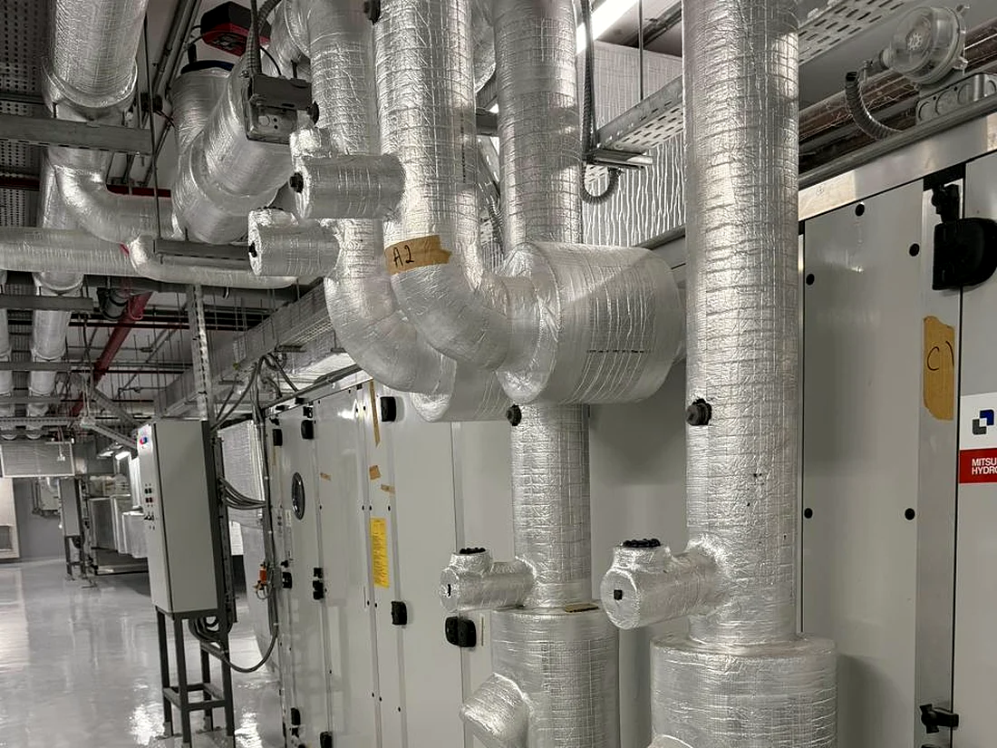 Air handling unit with insulated chilled water pipework and valves in a plant room installed and commissioned by Mecamac